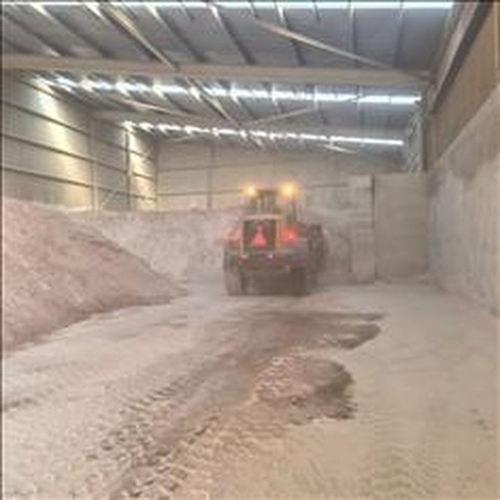 Wheel loader reclaiming fluorspar from warehouse stockpiles